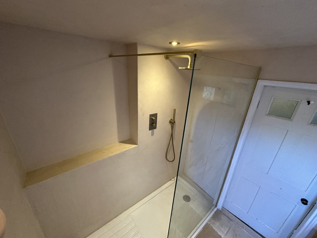 Walk-in shower with recessed shelf, glass screen and brass fittings