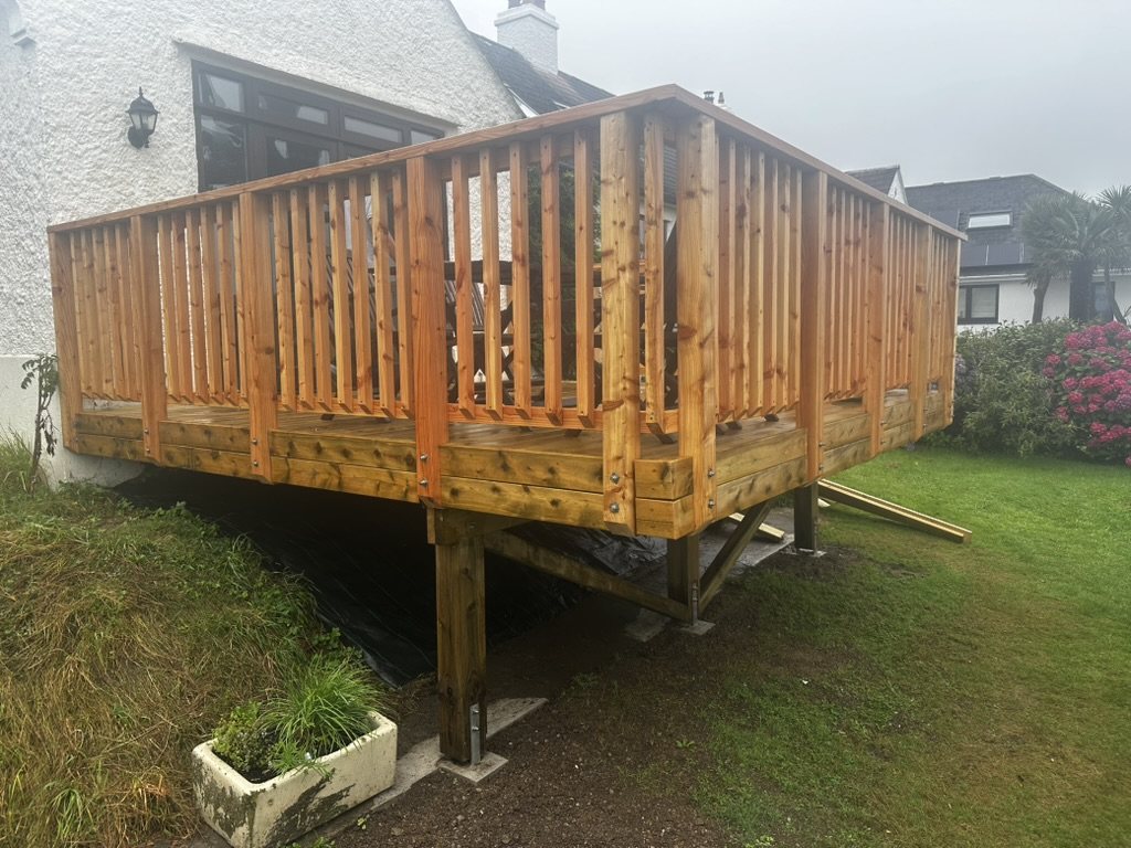 Finished raised timber deck with balustrade, standing on posts beside a white rendered house
