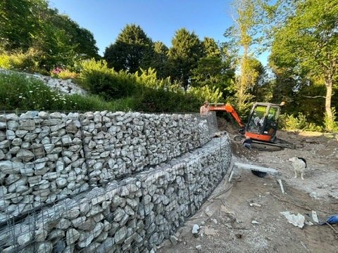 Finished tiered gabion retaining wall with a mini digger beyond