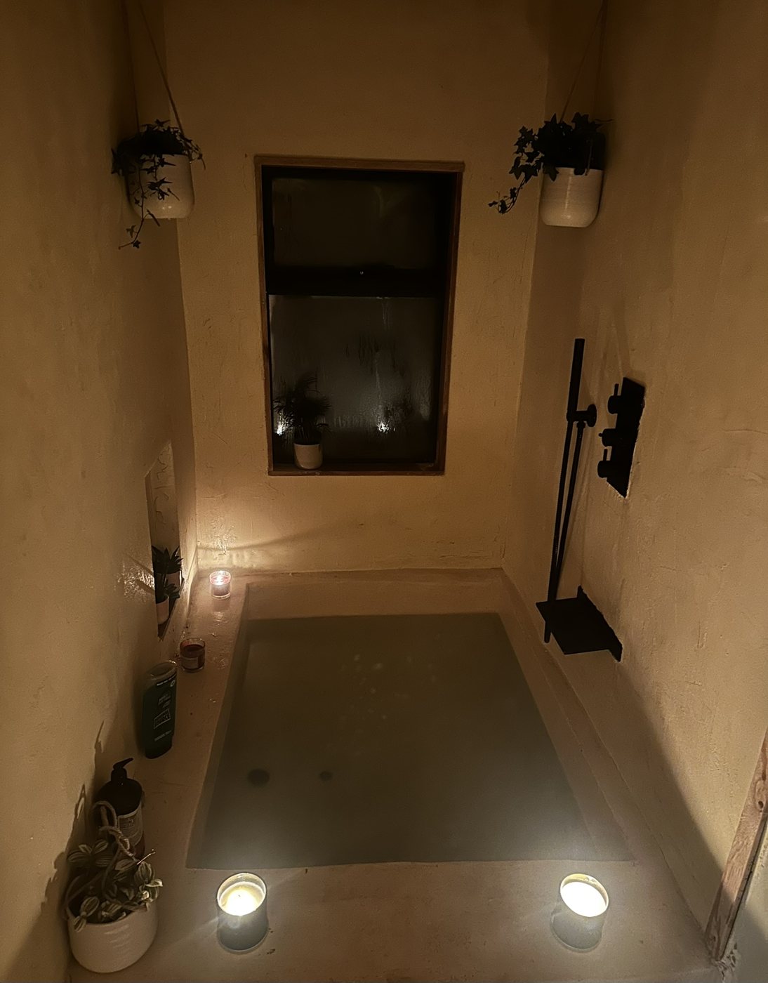 Sunken microcement bath in the Treehouse, lit by candles