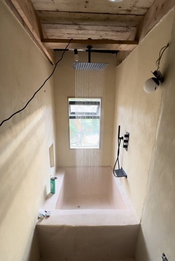 Rain shower running into the sunken microcement bath