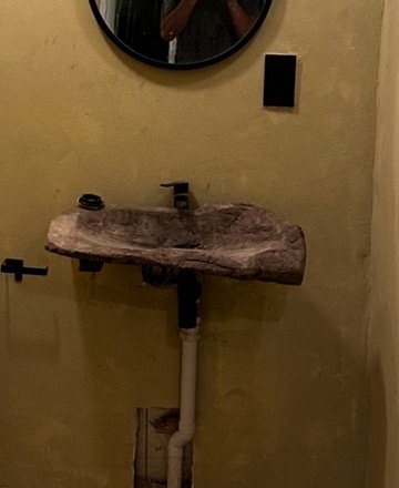 Hand-carved stone basin on a microcement wall