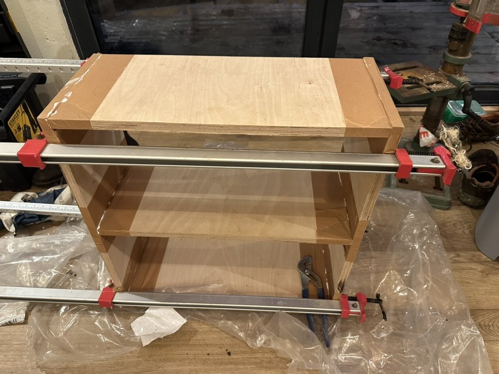 A birch plywood cabinet in clamps in the workshop